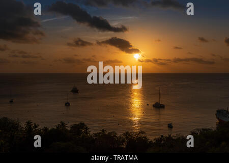 Tramonto tropicale oltre l'isola caraibica di Mustique. Colori intensi Foto Stock