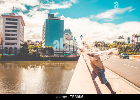 L'uomo gettando rete da pesca per la cattura di pesce sul fiume in piedi sopra il ponte Foto Stock