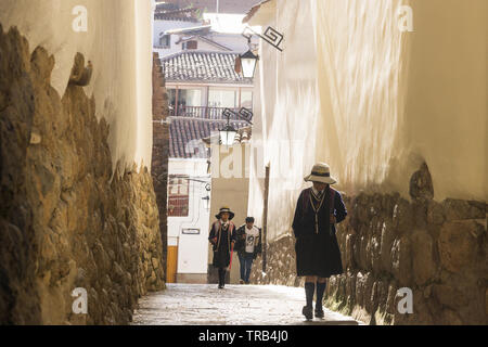 Cusco scena di strada - scolari in uniforme andare a scuola a piedi al mattino. Foto Stock