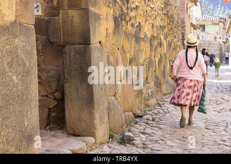 Donna Peruviana passeggiate lungo la pedonale strada inca di Ollantaytambo, Perù. Foto Stock