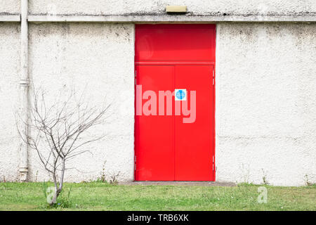 Uscita antincendio porta rossa e il muro bianco al posto di lavoro Foto Stock