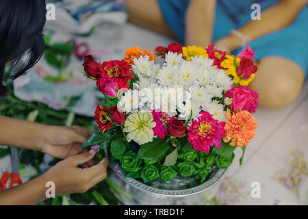 Gli studenti si aiutano a vicenda per creare un vassoio di fiori con il piedistallo per gli Insegnanti" Giorno Foto Stock