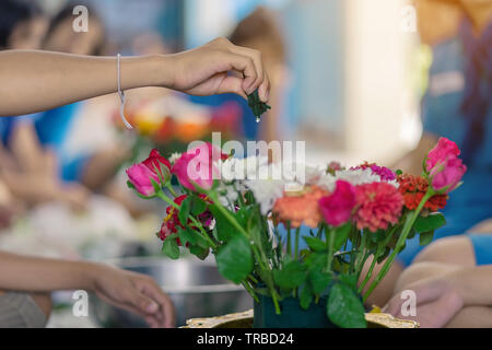 Gli studenti si aiutano a vicenda per creare un vassoio di fiori con il piedistallo per gli Insegnanti" Giorno Foto Stock