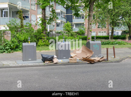 Oost di Amsterdam. Il lato est quartieri. Vista di tre contenitori per rifiuti per la separazione con un grande cartone vicino ad essa. La contaminazione di strada. Copyspace. Foto Stock