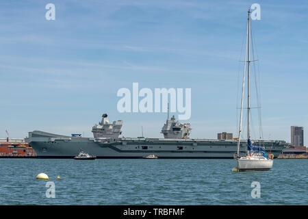 HMS Queen Elizabeth ormeggiata nel porto di Portsmouth con la pattuglia di polizia barche Foto Stock