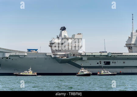 HMS Queen Elizabeth in Portsmouth Porto con tre barche di polizia di guardia, pronto per Donald trionfi visita di Stato il 5 giugno 2019 Foto Stock