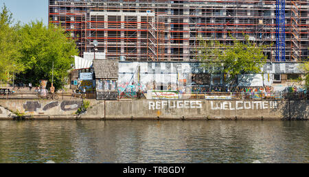 Berlino, Germania - 18 Aprile 2019: la gente visita YAAM night club con segno rifugiati Benvenuti! Lungo il fiume Spree. Berlino è la capitale e ampia Foto Stock