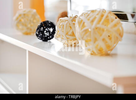 Decorative di giallo e nero forme diverse sfere, vimini da materiali naturali su un tavolo bianco all'interno del soggiorno di casa, chiudi immagine in alto Foto Stock