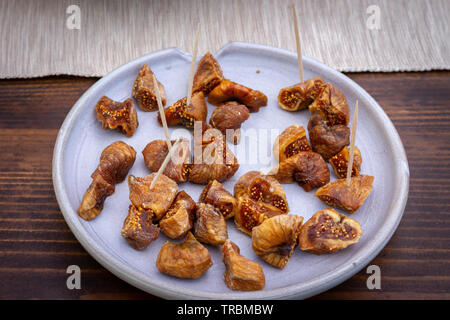 I fichi secchi in grigio di una piastra su un tavolo di legno. I fichi secchi sono molto comuni in Grecia. Foto Stock