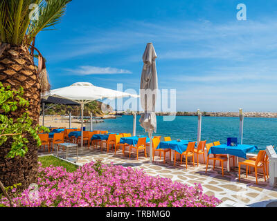 Tavoli con sedie in una tradizionale taverna Greca vicino al mare Foto Stock