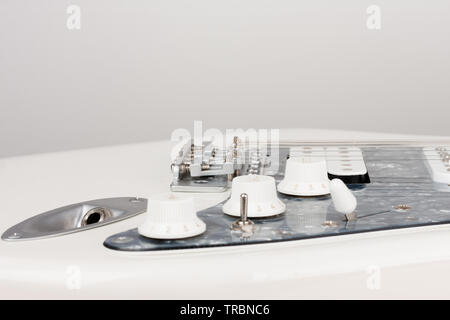 Chiudere il connettore di uscita su bianco chitarra elettrica, studio shoot. 2 x bobina singola e 1 x Humbucking. Perla nera pattipenna Foto Stock