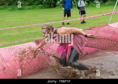 Warrington, Regno Unito. 2 Giugno 2019. Gara per la Vita 2019, Warrington, in aiuto della ricerca sul cancro. Donna di bagnare e fangoso in una mudpit Foto Stock