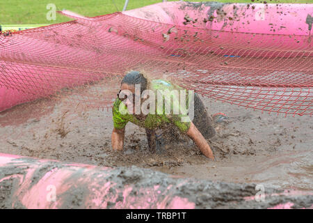 Warrington, Regno Unito. 2 Giugno 2019. Gara per la Vita 2019, Warrington, in aiuto della ricerca sul cancro. Donna di bagnare e fangoso in una mudpit Foto Stock