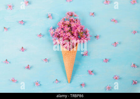 Gelato di fiore di rosa fiori di ciliegio nel cono di cialda su color pastello sfondo blu con boccioli. flat laici. vista dall'alto. matrimonio o sfondo per le vacanze Foto Stock