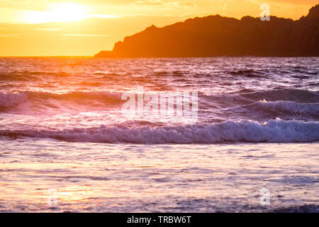 Onde che si infrangono sulla spiaggia al tramonto, il Whitesands Bay, St Davids, Pembrokeshire National Park, Wales, Regno Unito Foto Stock