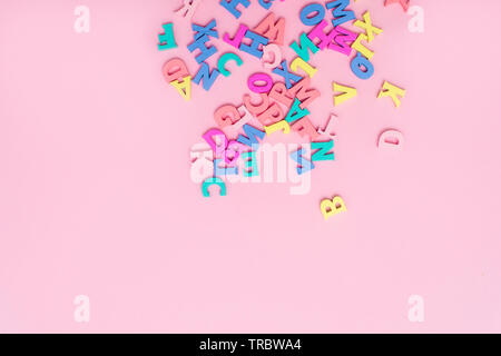 Molti variopinti lettere in legno su un sfondo rosa. toy lettere dell'alfabeto inglese. Vista da sopra. Lay piatto. Copia spazio per il testo Foto Stock