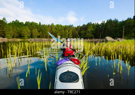 Fotografo Outdoor Zizza Gordon paddling in un kayak nel lago Vansjø, Østfold, Norvegia. Il lago Vansjø è il lago più grande in Østfold. Vansjø e i suoi dintorni di laghi e fiumi sono una parte dell'acqua sistema chiamato Morsavassdraget. Giugno, 2010. Foto Stock