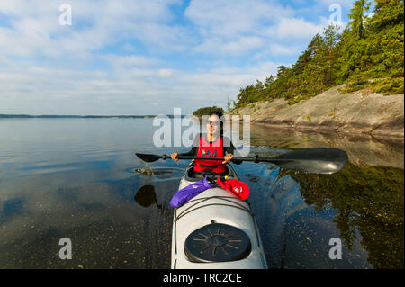 Fotografo Outdoor Zizza Gordon paddling in un kayak nel lago Vansjø, Østfold, Norvegia. Il lago Vansjø è il lago più grande in Østfold. Il lago Vansjø e i suoi dintorni di laghi e fiumi sono una parte dell'acqua sistema chiamato Morsavassdraget. Giugno, 2010. Foto Stock