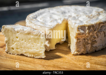 Un close-up di un morbido formaggio francese tagliato su un pannello di legno Foto Stock