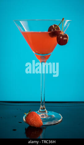 Un cocktail di rosso in un bicchiere alto con sfondo blu Foto Stock