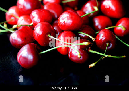 Mature ciliegio dolce bacche con gocce di acqua su un sfondo scuro vicino fino Foto Stock