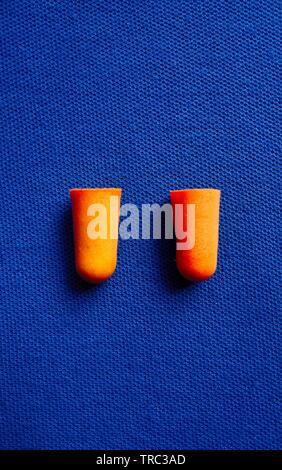 Orange i tappi per le orecchie isolato su blu Foto Stock