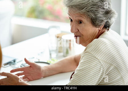 Senior donna seduta in clinica Foto Stock