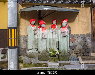 Sei statue in pietra di san Ojizou indossa cappuccio rosso e la bib, protettore dei bambini e il protettore dei viaggiatori e a un tempio, Giappone. Foto Stock