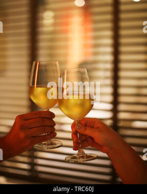 Coppia giovane con due bicchieri di vino bianco nel letto sullo sfondo sfocato. Spazio di copia Foto Stock