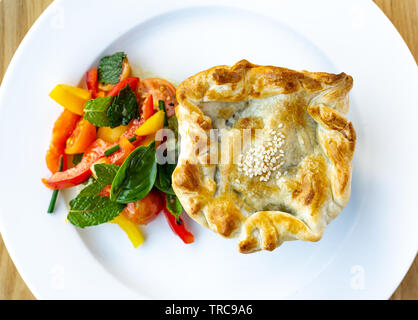 Bella casa fatta di pollo e torta a fungo con menta fresca, basilico, pomodoro e insalata di capsicum. Foto Stock