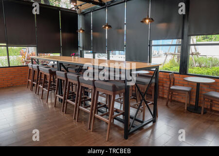 Tavolo in legno con sedie e lampada di illuminazione in coffee shop Foto Stock