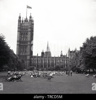 1960s, storico, vista sui giardini della Victoria Tower con persone in sedie a sdraio seduti sull'erba, Westminster, Londra, Inghilterra, Regno Unito. La bandiera di Union Jack vola sulla cima della torre, che si trova accanto al Palazzo di Westminster. Foto Stock