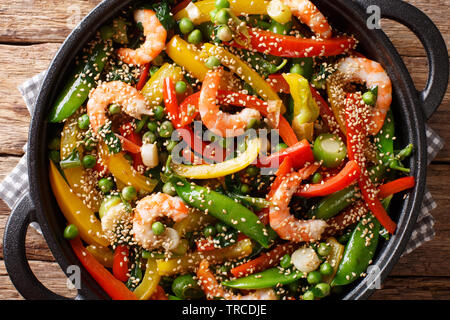 Gamberi arrosto con peperoni, cipolle, erbe, pod piselli, sesamo close-up in una padella sul tavolo. parte superiore orizzontale vista da sopra Foto Stock