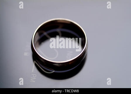 Il impegnato un anello di fidanzamento si siede in cima a un cellulare di visualizzazione di data e ora. Foto Stock