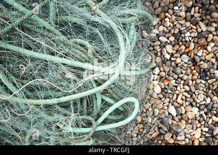 Green nylon plastic fishing nets and rope on a beach Foto Stock