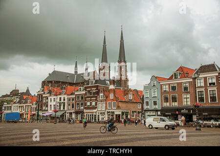 La gente sulla piazza del mercato, edifici in mattoni con negozi e steeple in Delft. Grazioso villaggio pieno di canali e di architettura gotica in Paesi Bassi. Foto Stock