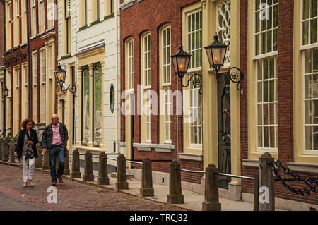 Giovane camminando sulla strada con elegante bifamiliari edifici in mattoni di Delft. Grazioso villaggio pieno di canali e di architettura gotica in Paesi Bassi. Foto Stock