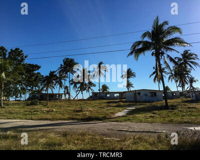 Sole oltre il abbandonate case vacanza e palme vicino a Playa Coco in Playa Giron, Cuba Foto Stock