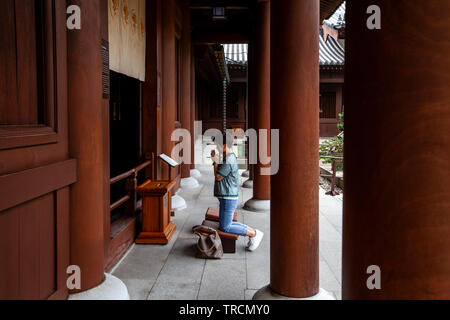 Una donna orante presso il Chi Lin Monastero, Hong Kong, Cina Foto Stock