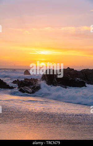 Le onde in movimento sulla riva come i tramonti all'orizzonte lungo la famosa strada statale uno vicino a Big Sur in California Foto Stock