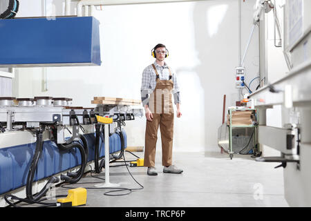 Carpenter l uomo lavora con doghe in legno in falegnameria, con controllo numerico computerizzato centro, macchina CNC, isolato su sfondo bianco Foto Stock