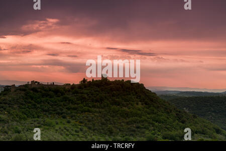 Mura e torri medievali della città di Monticchiello in Toscana durante un acquazzone al tramonto Foto Stock