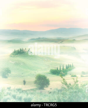 Alba in una nebbiosa valle con vista sul Bevedere villa sulle colline vicino a Pienza Foto Stock