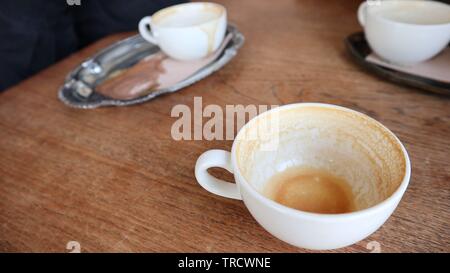 Svuotare le tazze di caffè su di un tavolo di legno Foto Stock