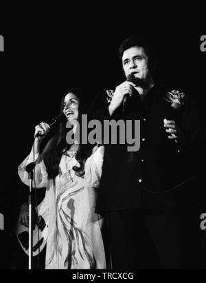 Amsterdam, Paesi Bassi: American chitarrista e cantante Johnny Cash (1932-2003) con la moglie June Carter esibirsi dal vivo sul palco in Amsterdam, Paesi Bassi. 11-04-1976. (Foto di Gijsbert Hanekroot) Foto Stock