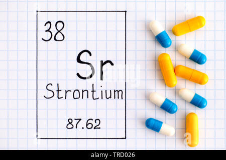 La grafia elemento chimico stronzio Sr con alcune pillole. Close-up. Foto Stock