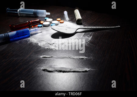 Il concetto di droga, cocaina, iniezione,tabella, cucchiaio sul tavolo scuro Foto Stock