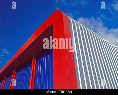Rosso in acciaio telaio curvo ad angolo commerciale industriale magazzino edificio con forma arrotondata di colore argento laterale del tetto e dei pannelli di rivestimento England Regno Unito Foto Stock