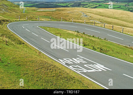 Paese bilingue su strada le marcature di sicurezza rallentare i segni sulla strada asfaltata di avvertimento del tornante in strada in campagna gallese Brecon Beacons Wales UK Foto Stock