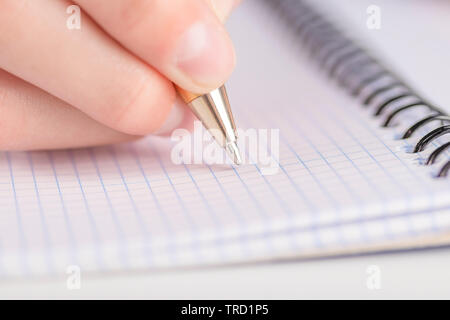 Teen scrive nero giallo penna in un notebook a scacchi. Compiti e piano giornaliero Foto Stock